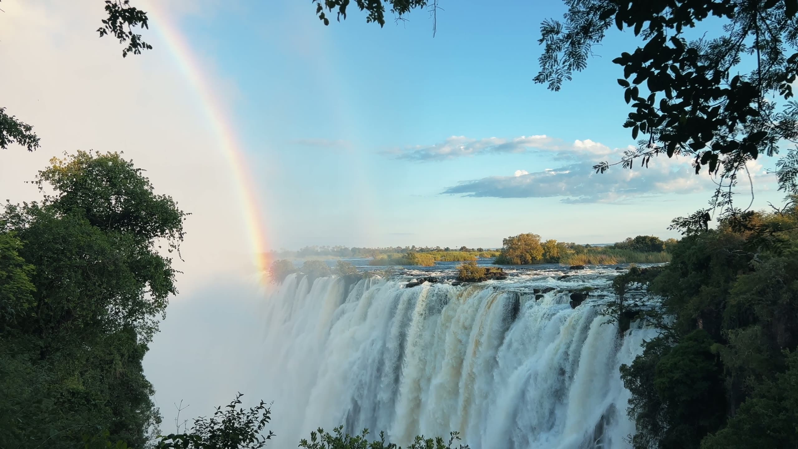 Golden-hour view of Victoria Falls spray rising over the Zambezi River